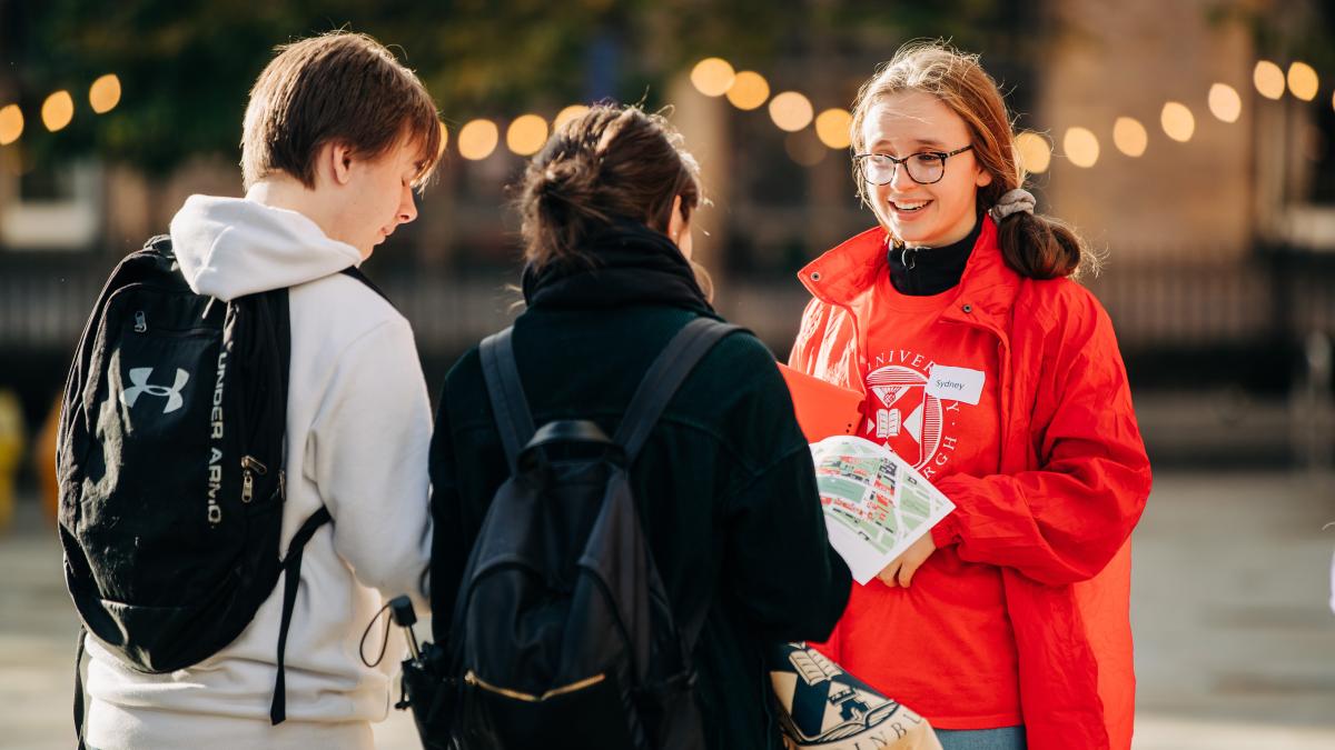 Student Ambassador in a red hoodie speaking to 2 visitors at Open Day