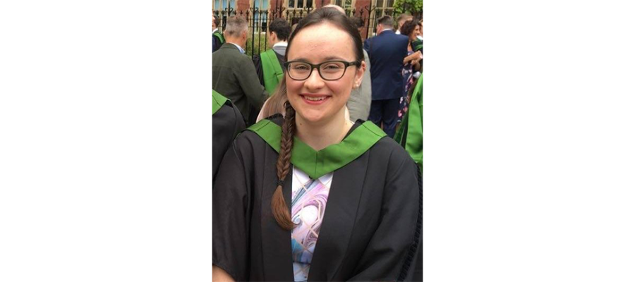 Bethan Highley standing in a graduation gown and smiling.