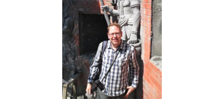 Dr. David Radford standing next to a statue and smiling.
