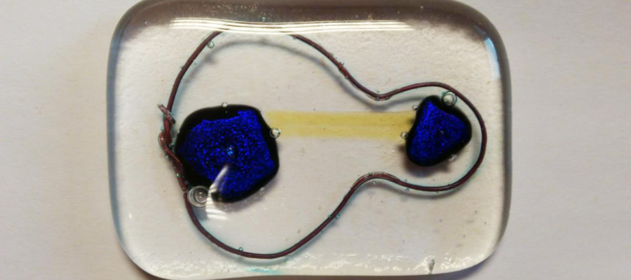 A glass pebble with cellular structure in blue, yellow and copper wire inside