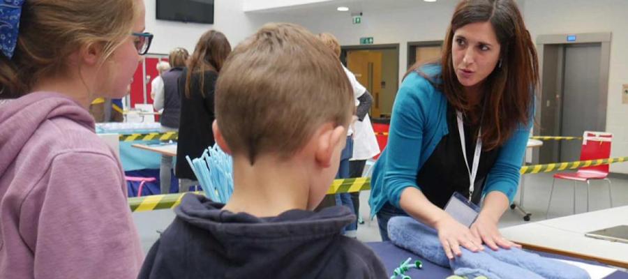 Researcher showing two children a cell model