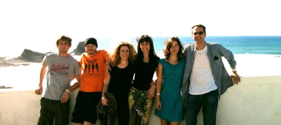 Lab group members pose for a group photo in front of a wall overlooking the sea