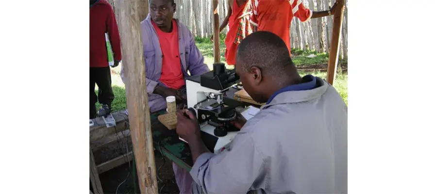 Man looking through a microscope outdoors.
