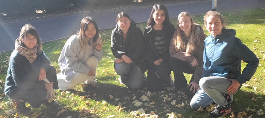 Julie and the lab group members in a group photo crouched down on grass