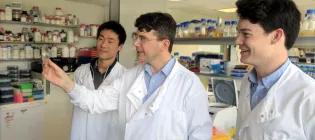 Professor Chris French and two research students looking at a petri dish inside a lab