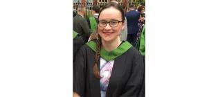 Bethan Highley standing in a graduation gown and smiling.