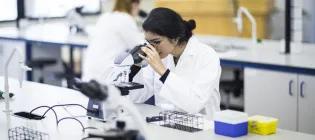 A Biomedical Science Student Looking into a Microscope in a Lab