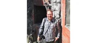 Dr. David Radford standing next to a statue and smiling.