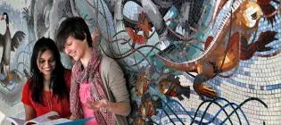 A Student and Teacher Looking at a Notebook in front of a Grafitti Wall