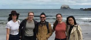 Photo of 5 lab group members posed fr a photo in front of the sea, Bass rock in the background