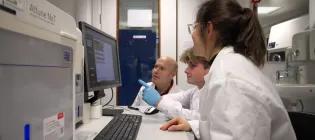 Three researchers looking at an attune flow cytometer