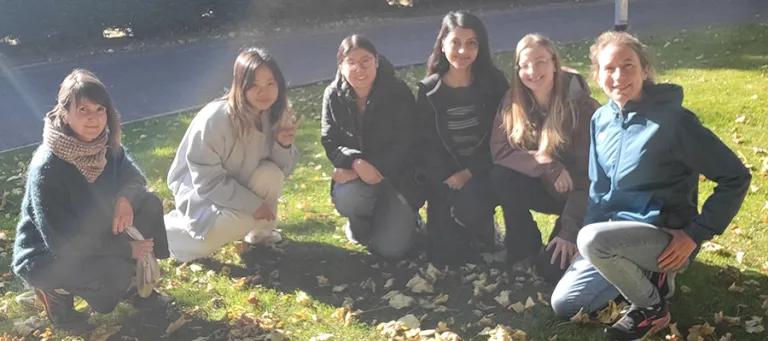 Julie and the lab group members in a group photo crouched down on grass