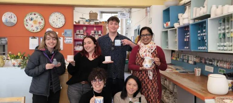 Photo from a lab social pottery painting day out, showing group members with their painted pottery
