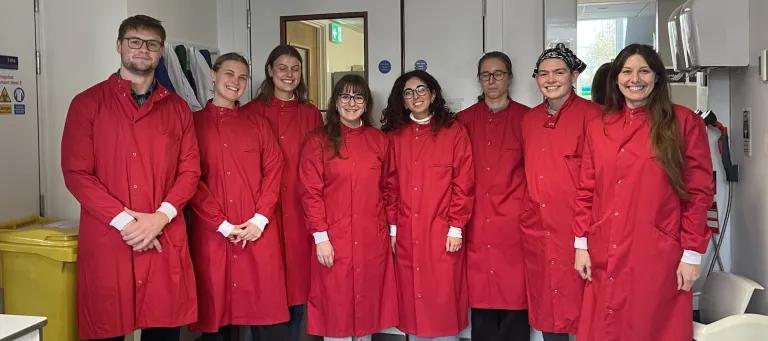Image of Lab group members in red lab coats 