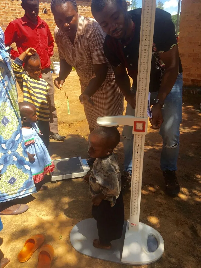 Photo of a toddler being measured by two health care workers