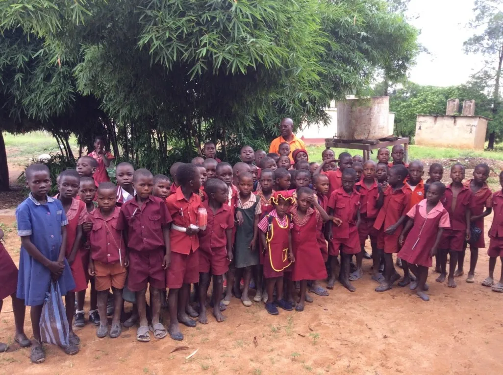 Photo of a group of school children gathered outside, they wear their burgandy school unifors