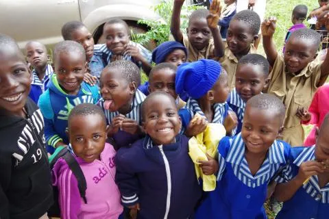 A group of schoolchildren stand in front of a vehicle 