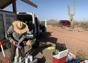 Photo of Jsh doing work in the field, surrounded by desert and cacti