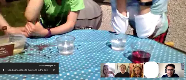Three children doing an experiment supervised by scientists during a call.