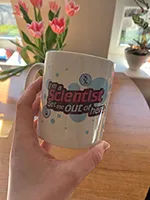 Photo of a hand holding a mug with \"I'm a scientist get me out of here\" logo on it