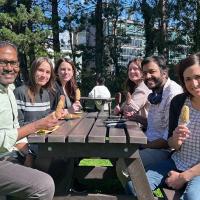 Six group members sit at a picnic bench eating ice creams.