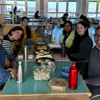 Group members sit around a table to share a meal with their Nepalese visitor