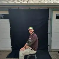 Man sat on a stool in front of a black photography background