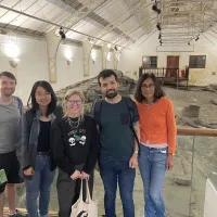 Five people stand infront of fossilised trees at Fossil Grove, Glasgow