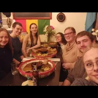 Photo of the project group members sitting at a table in a restaurant with large dishes of food on it