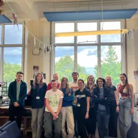 Group photo of the fieldworkers in a room with large windows overlooking trees