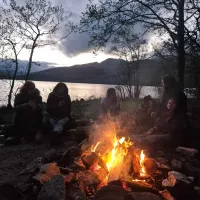 A bonfire is surrounded by some lab members next to Loch Tay