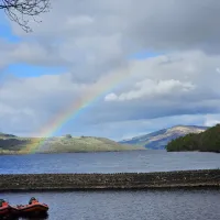 Image of a rainbow over Loch Tay, 2 speedboats sit in the harbour at the front of the image