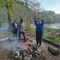 Taylor from the Hardwick lab enthusiastically holds up a log ready to assemble the bonfire