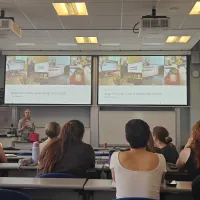 Photograph of a lecture on panel design and analysis, with colourful flow cytometry examples displayed on projection screens.