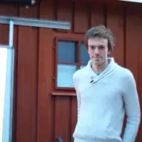 A lab member stands outside a chalet in a winter jumper