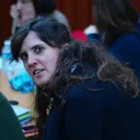 A lab member, sat at a table with other group members, turns to look at the camera