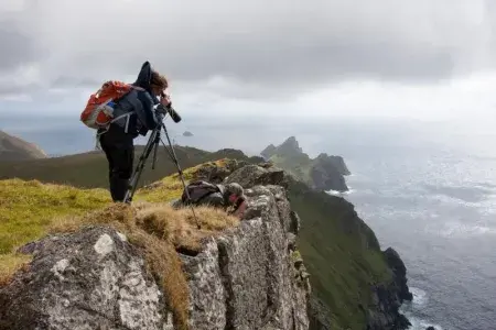 Two researchers standing on the edge of a hill censusing the sheep head count.
