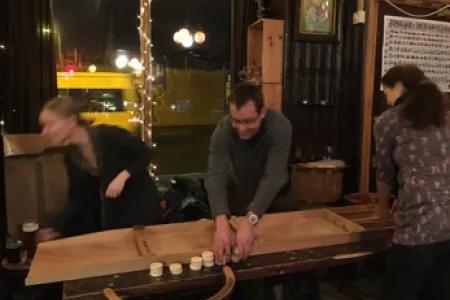 Photo of 3 lab group members playing a game of Sjoelen in the pub