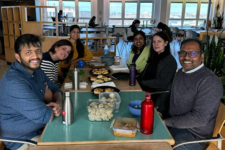Group members sit around a table to share a meal with their Nepalese visitor