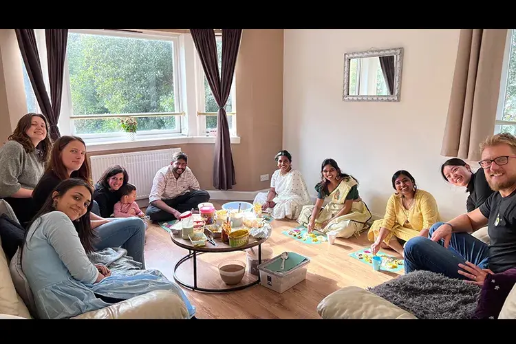 Group members gathered ina home to eat around a small table.