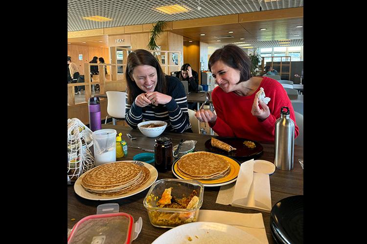 Two group members share a joke whilst enjoying pancakes.