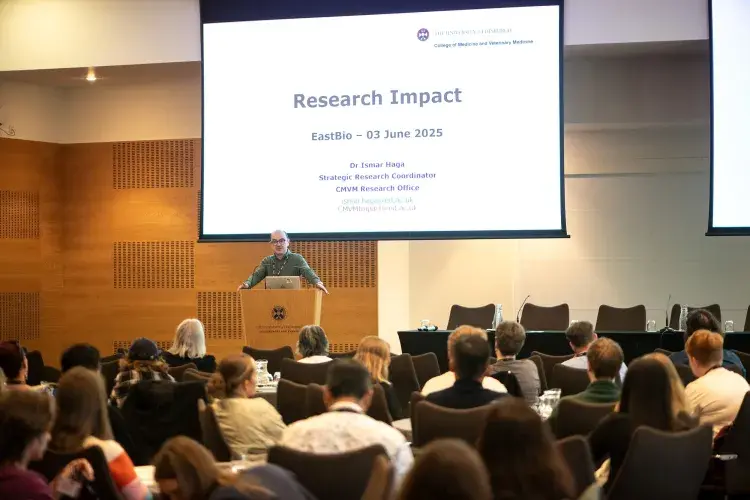 Image of Ismar Haga presenting in front of screen reading Research Impact
