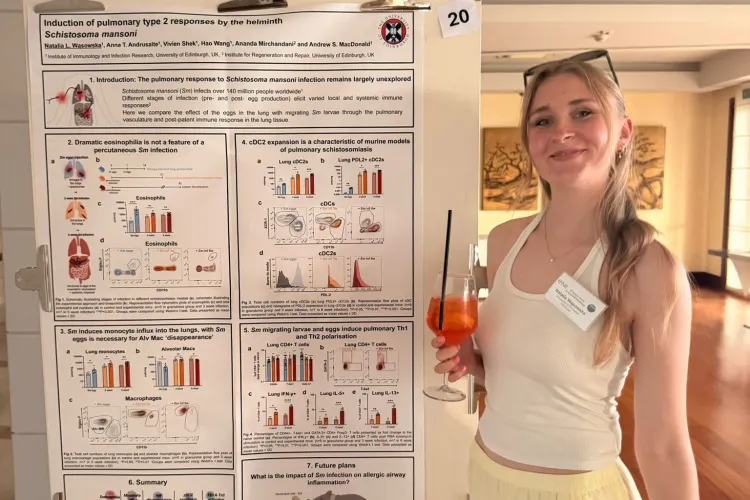 A person standing next to a research poster titled “Induction of pulmonary type 2 responses by the helminth Schistosoma mansoni,” featuring graphs, diagrams, and tables summarising immune response data.
