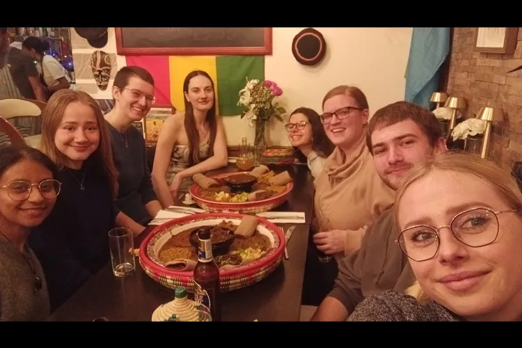 Photo of the project group members sitting at a table in a restaurant with large dishes of food on it
