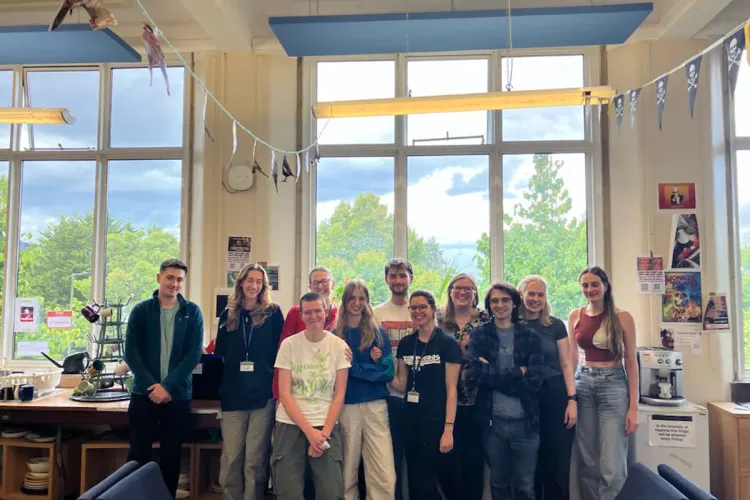 Group photo of the fieldworkers in a room with large windows overlooking trees