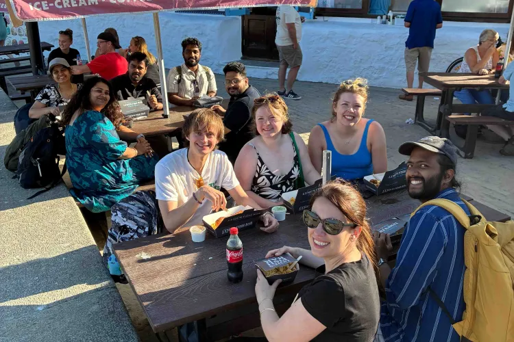 The Hardwick lab and friends sitting at picnic tables enjoying some fish and chips on a sunny day