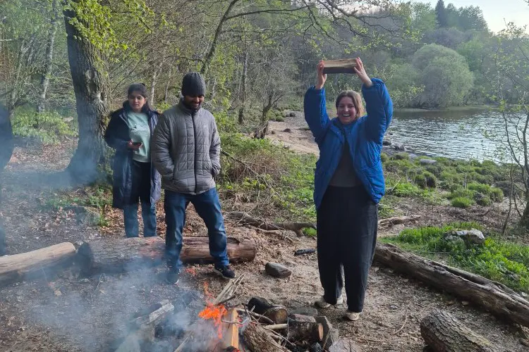 Taylor from the Hardwick lab enthusiastically holds up a log ready to assemble the bonfire