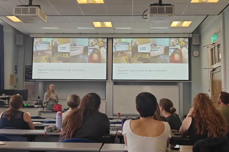 Photograph of a lecture on panel design and analysis, with colourful flow cytometry examples displayed on projection screens.
