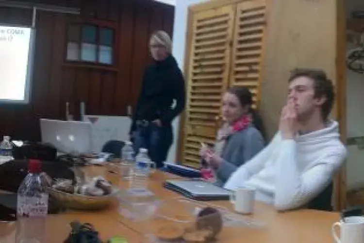 Panorma photo of the lab group sitting around a table indoors