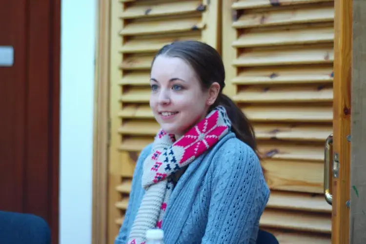 A lab member sitting indoors wearing a colourful winter scarf